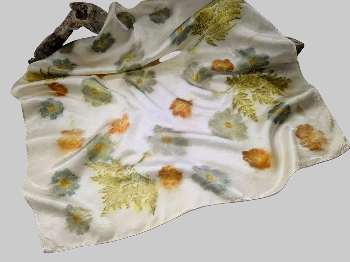 Floral-patterned fabric draped over a branch on a light gray background
